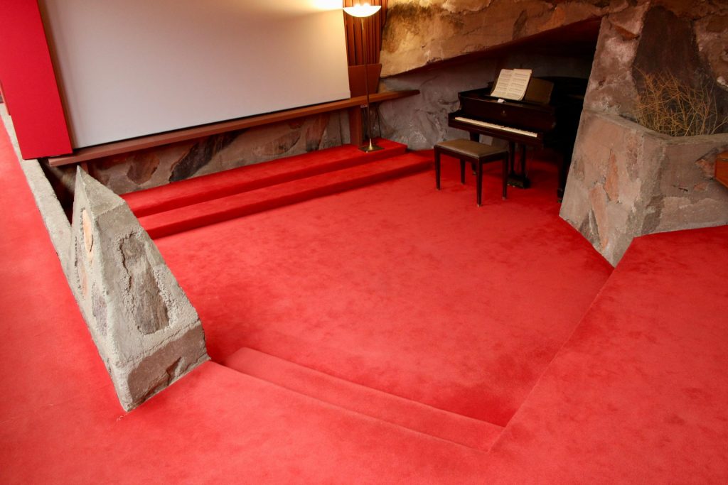Red carpeted room with a grand piano.