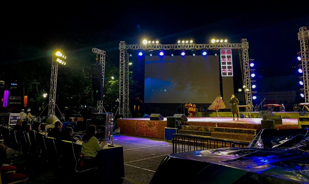 Outdoor stage setup with screen and audience at night
