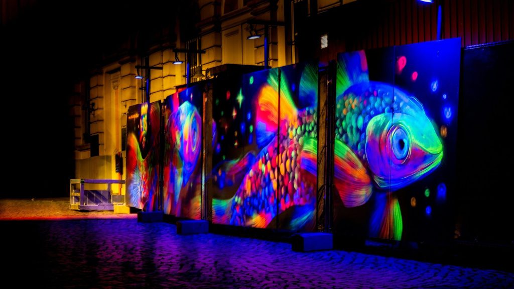 Vibrant neon fish art on dark walls